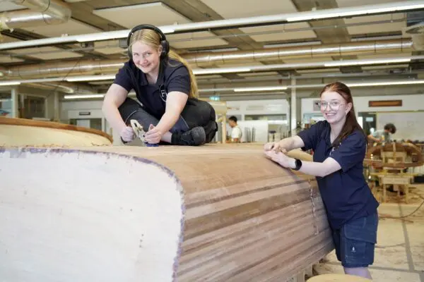 Twee studenten die werken met de schaaf aan hun boot.