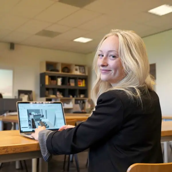 Een student van het Hout en Meubileringscollege die achter de computer zit.
