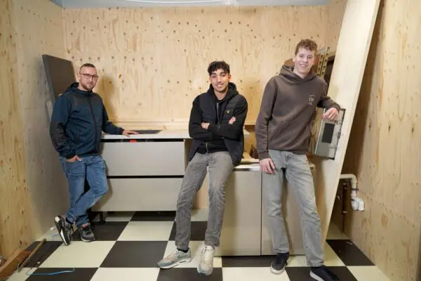 Drie studenten die leunen tegen een keuken