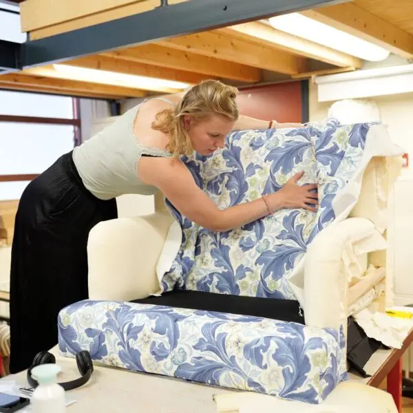 Een student van het Hout en Meubileringscollege stoffeert een fauteuil.