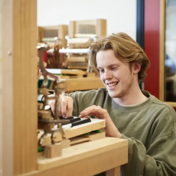 Student die een piano aan het stemmen is.