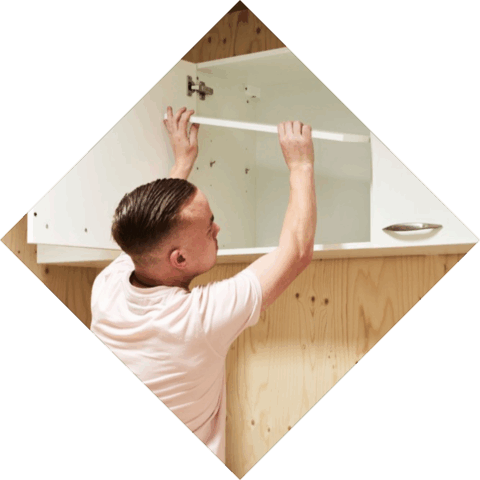 Student legt een plank in een hoog keukenkastje