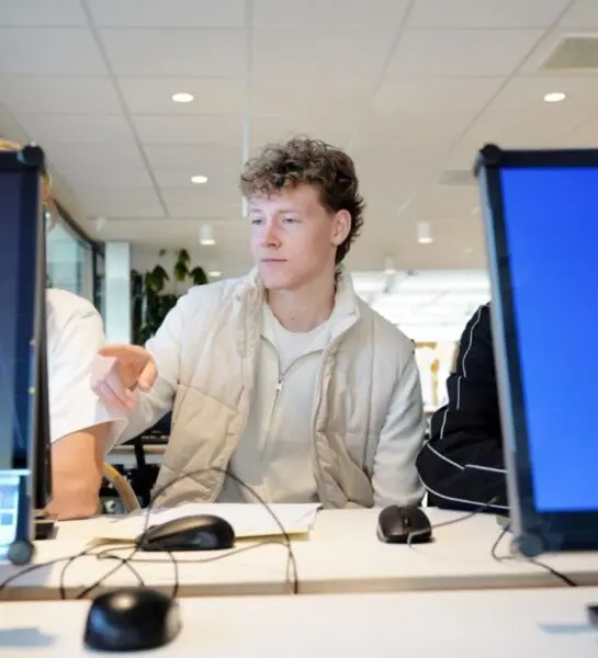 Student kijkt op computer en wijst