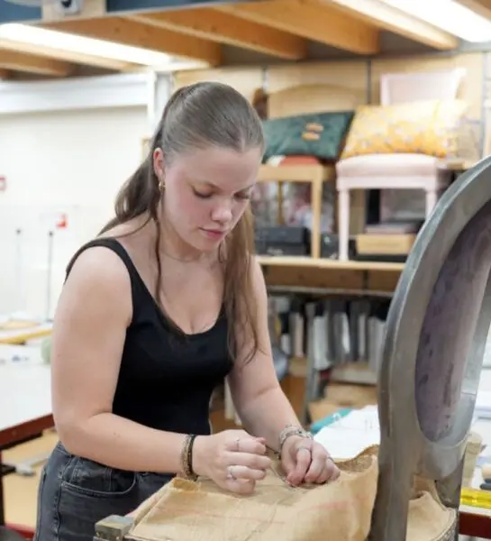 Student is bezig met het stofferen van een stoelzitting