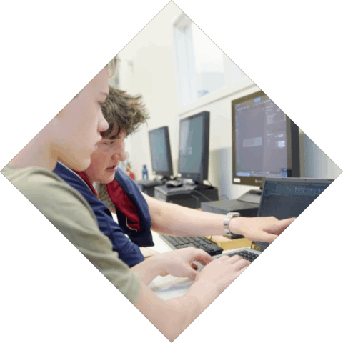 2 studenten werken achter de computer en zijn met elkaar aan het overleggen