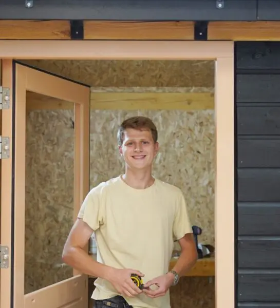 Student is met een rolmaat aan het meten en kijkt in de camera